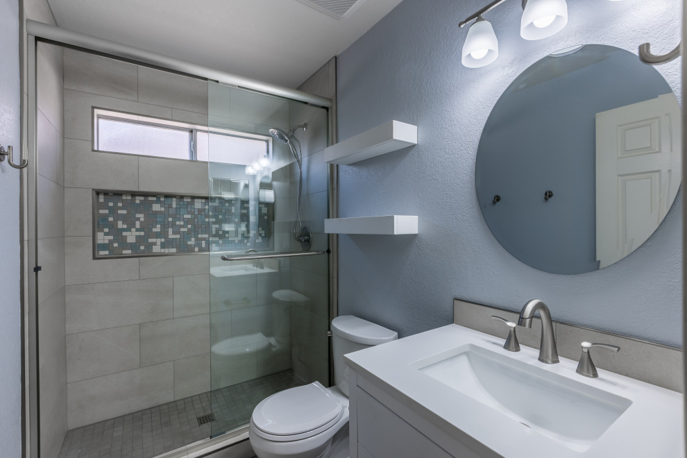 Idée de décoration pour une grande douche en alcôve principale tradition avec un placard à porte plane, des portes de placard blanches, WC séparés, un carrelage gris, des carreaux de porcelaine, un mur bleu, un sol en carrelage de porcelaine, un lavabo encastré, un plan de toilette en marbre, un sol gris, une cabine de douche à porte coulissante, un plan de toilette blanc, une niche, meuble simple vasque et meuble-lavabo sur pied.