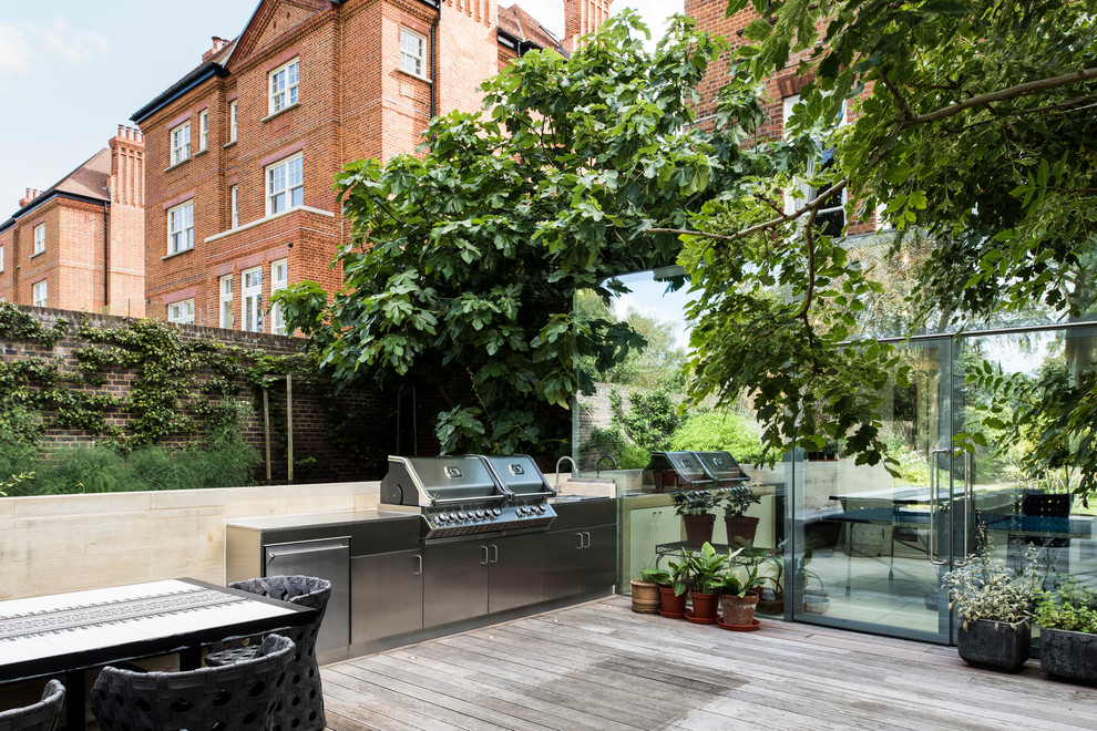 Eclectic backyard patio in London with an outdoor kitchen and no cover.