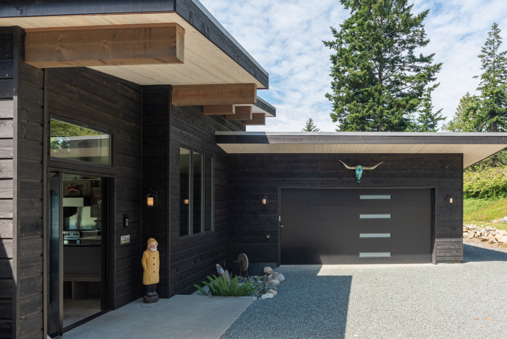 Mittelgroßes, Zweistöckiges Modernes Haus mit schwarzer Fassadenfarbe, Pultdach, Blechdach, grauem Dach und Verschalung in Seattle
