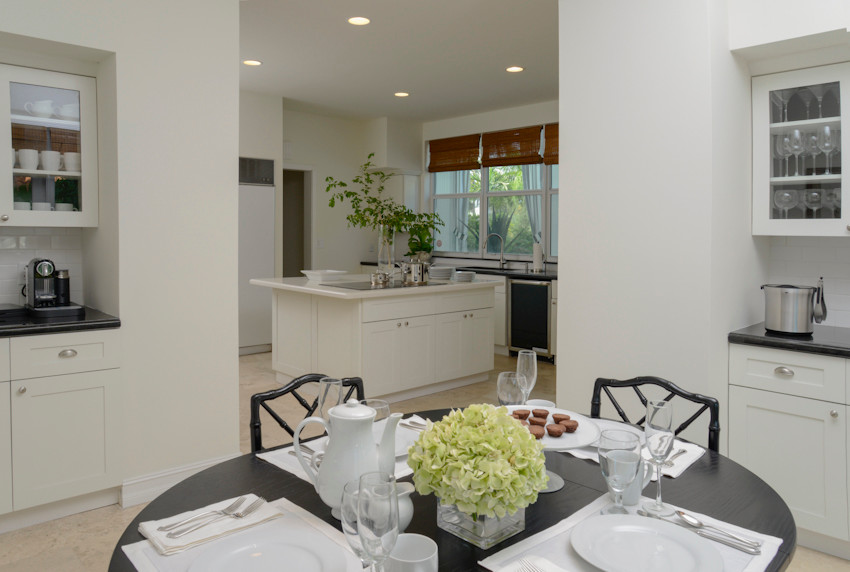 Eat-in kitchen - mid-sized transitional l-shaped eat-in kitchen idea in Miami with shaker cabinets, white cabinets, granite countertops, white backsplash, stainless steel appliances and an island