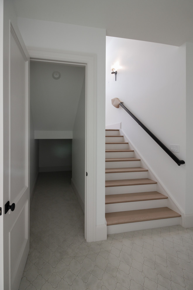 На фото: большая п-образная лестница в стиле модернизм с деревянными ступенями, крашенными деревянными подступенками, перилами из смешанных материалов и панелями на стенах с