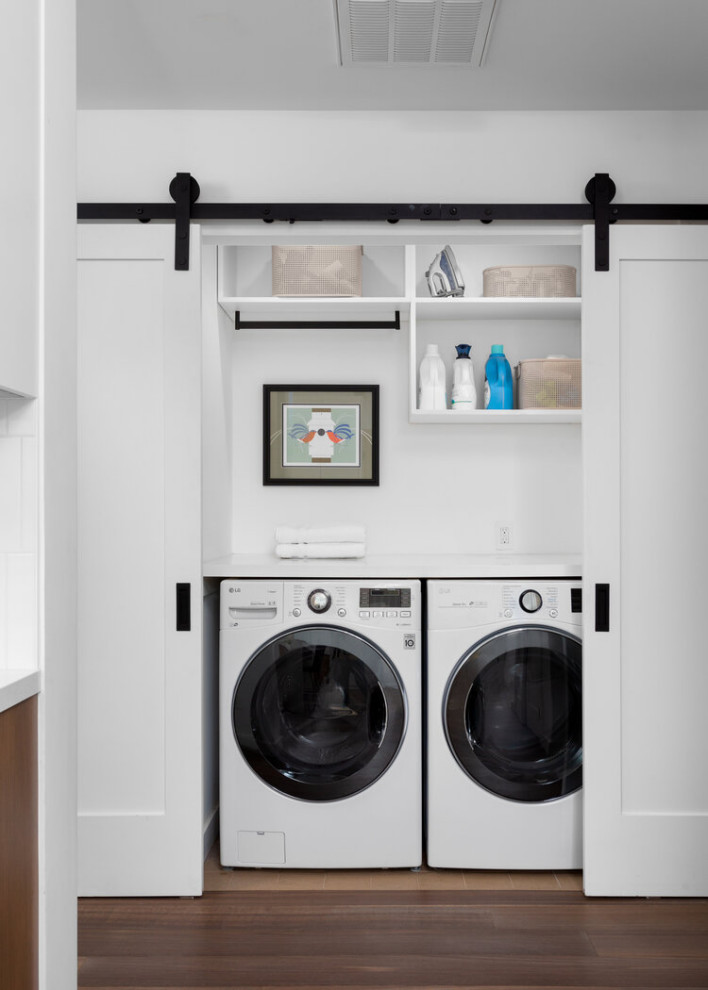 Mid-sized contemporary single-wall laundry cupboard in Los Angeles with marble benchtops, white walls, porcelain floors, a side-by-side washer and dryer, brown floor and white benchtop.