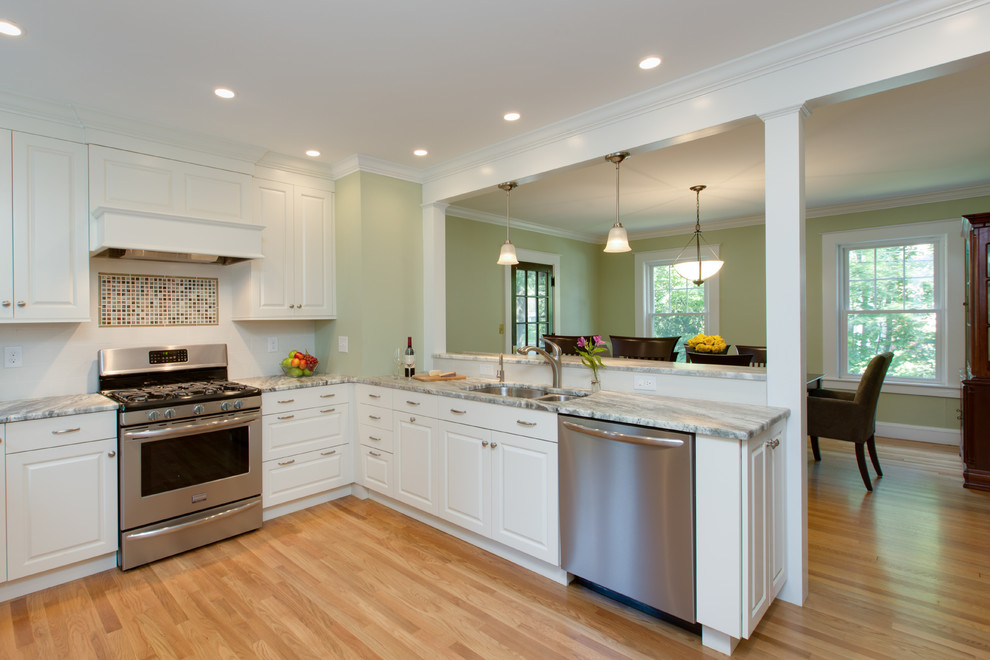 Transitional u-shaped medium tone wood floor eat-in kitchen photo in Boston with an undermount sink, raised-panel cabinets, white cabinets, granite countertops, white backsplash, subway tile backsplash and stainless steel appliances
