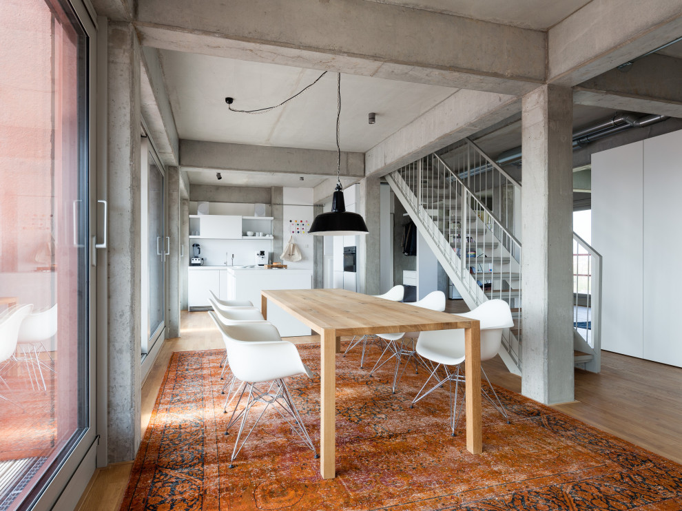 Photo of an industrial dining room in Berlin with grey walls, medium hardwood flooring and brown floors.