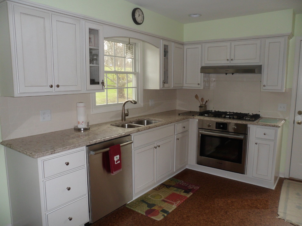 Photo of a mid-sized traditional l-shaped separate kitchen in Grand Rapids with a double-bowl sink, beaded inset cabinets, beige cabinets, granite benchtops, beige splashback, ceramic splashback, stainless steel appliances, cork floors and no island.