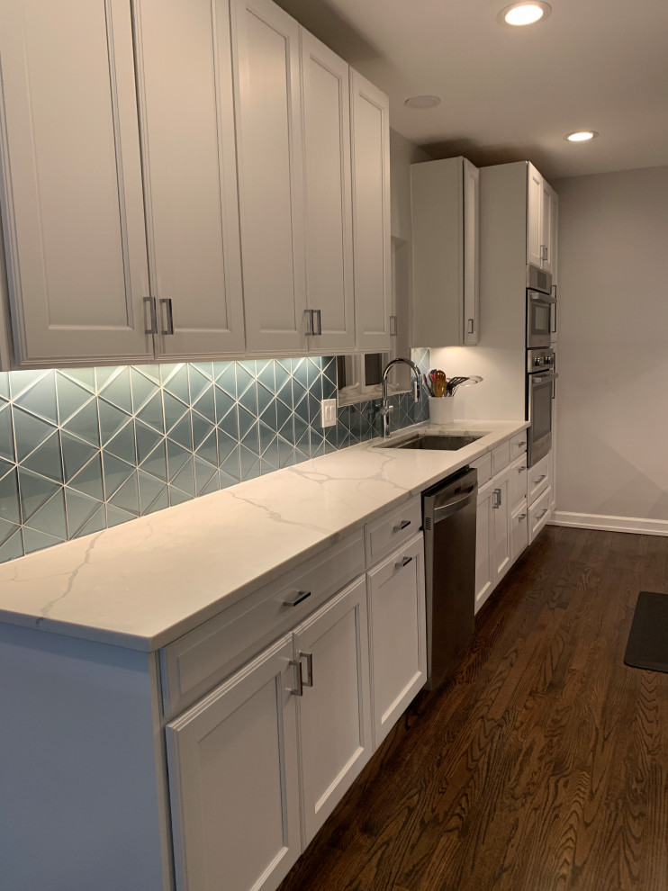 Inspiration for a mid-sized modern kitchen in Chicago with a single-bowl sink, shaker cabinets, blue cabinets, quartz benchtops, blue splashback, glass tile splashback, dark hardwood floors, with island, brown floor and white benchtop.