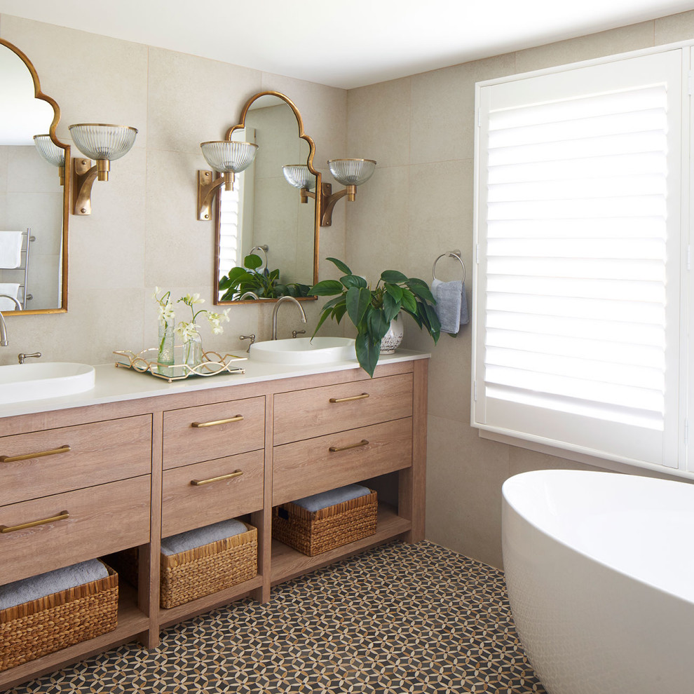 Design ideas for a large beach style master bathroom in Central Coast with brown cabinets, a freestanding tub, beige tile, stone tile, beige walls, ceramic floors, a drop-in sink, marble benchtops, multi-coloured floor, beige benchtops, a double vanity and a freestanding vanity.