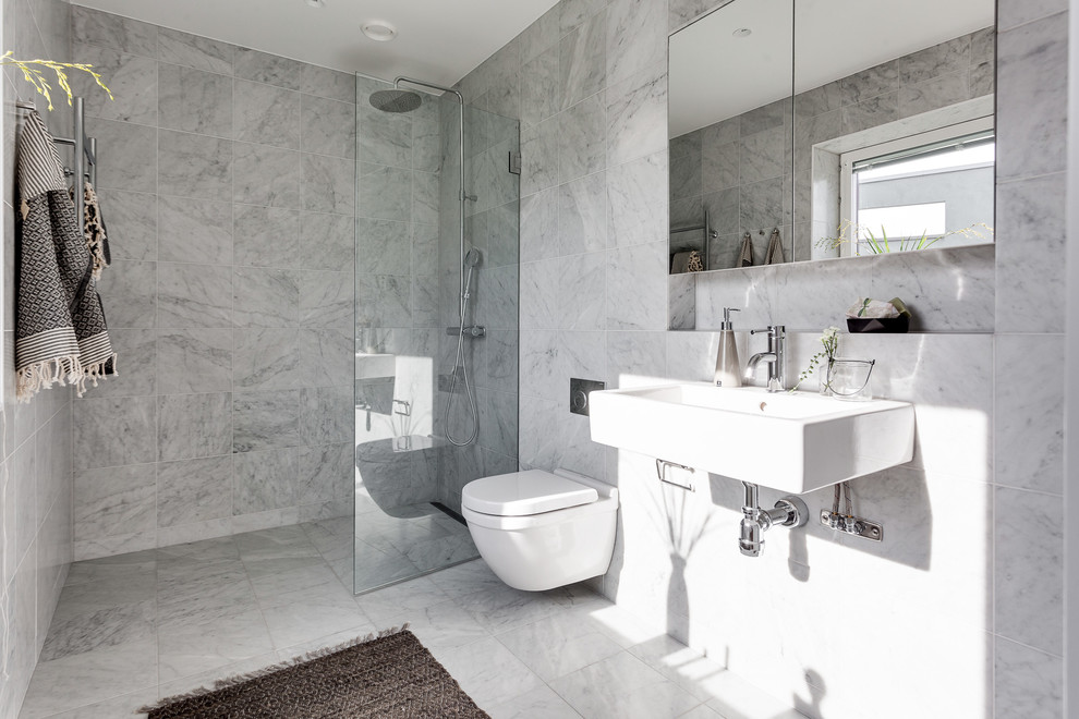 Inspiration for a mid-sized contemporary bathroom in Stockholm with flat-panel cabinets, a corner shower, a wall-mount toilet, gray tile, grey walls, marble floors, an integrated sink and an open shower.
