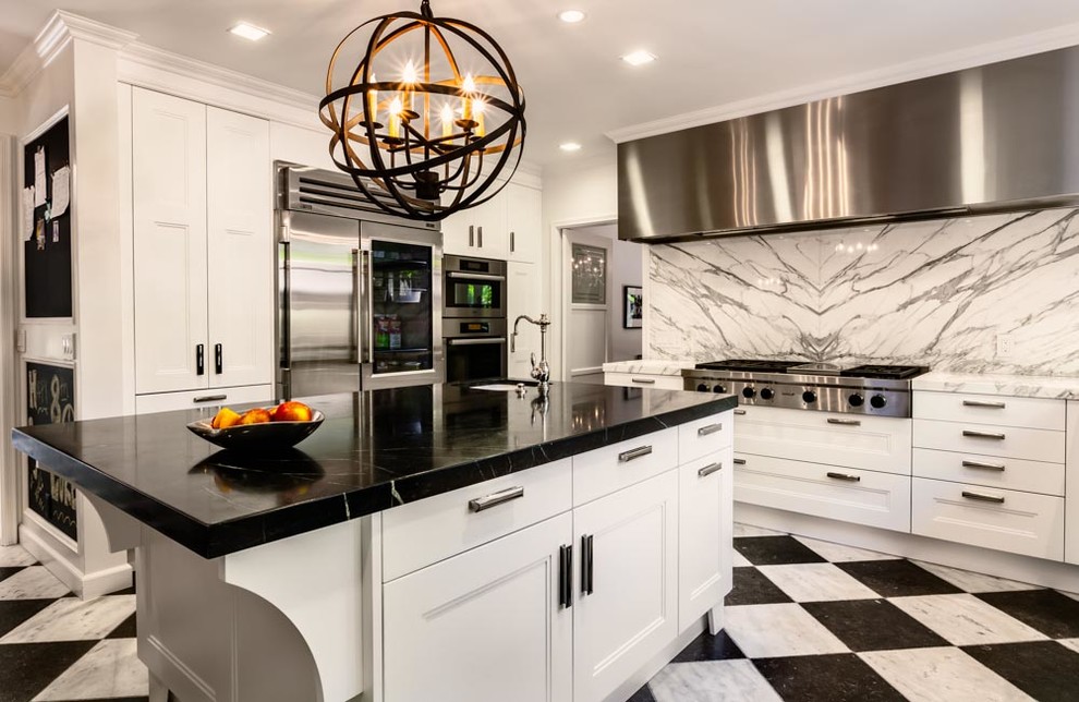 Photo of an expansive eclectic u-shaped open plan kitchen in Los Angeles with a farmhouse sink, recessed-panel cabinets, white cabinets, soapstone benchtops, stone slab splashback, stainless steel appliances, marble floors and with island.
