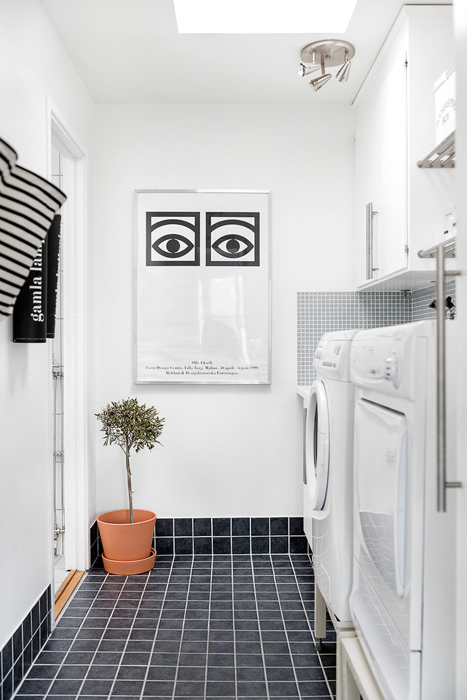 Design ideas for a mid-sized scandinavian single-wall utility room in Orebro with flat-panel cabinets, white cabinets, white walls, porcelain floors and a side-by-side washer and dryer.