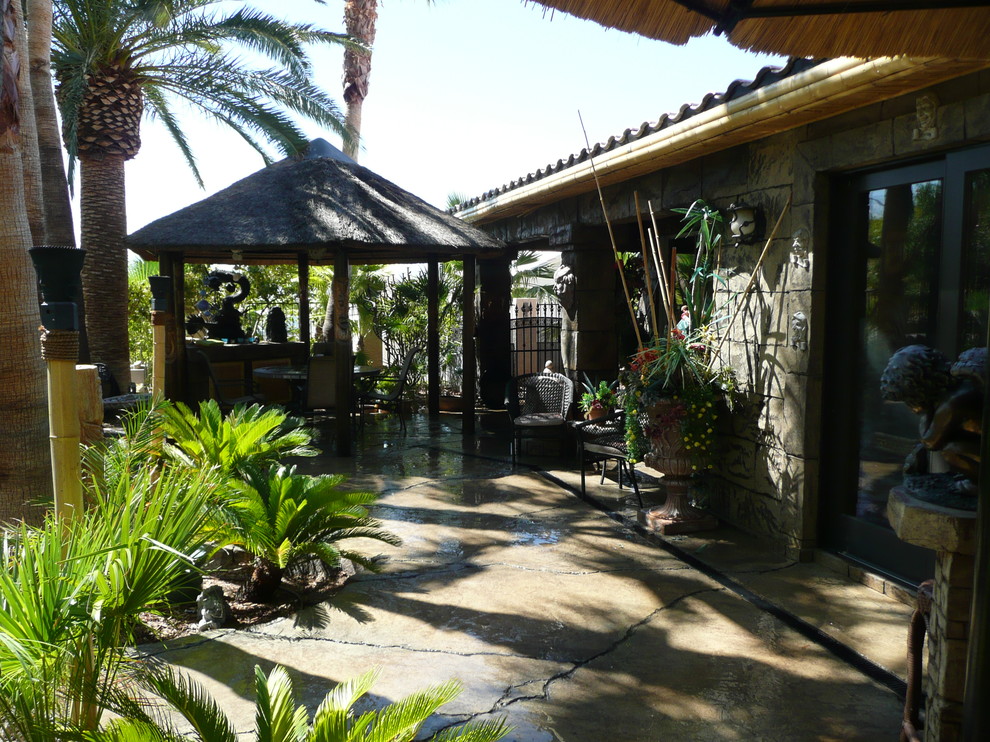 This is an example of a mid-sized tropical backyard patio in Los Angeles with an outdoor kitchen, stamped concrete and a gazebo/cabana.