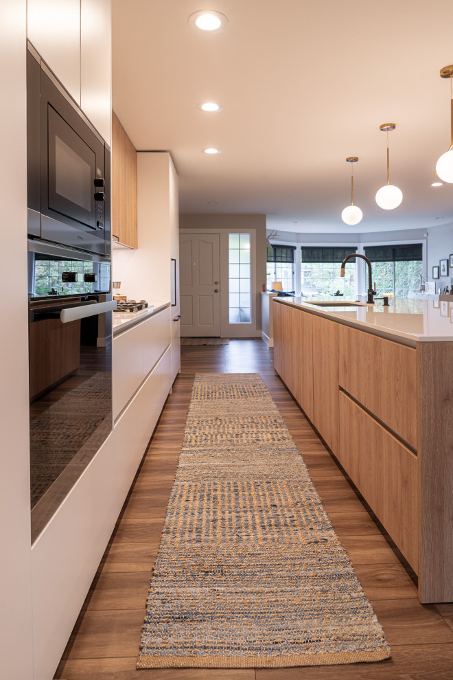 Inspiration for a large contemporary single-wall open plan kitchen in Portland with an undermount sink, flat-panel cabinets, white cabinets, quartz benchtops, white splashback, engineered quartz splashback, panelled appliances, vinyl floors, with island, brown floor and white benchtop.