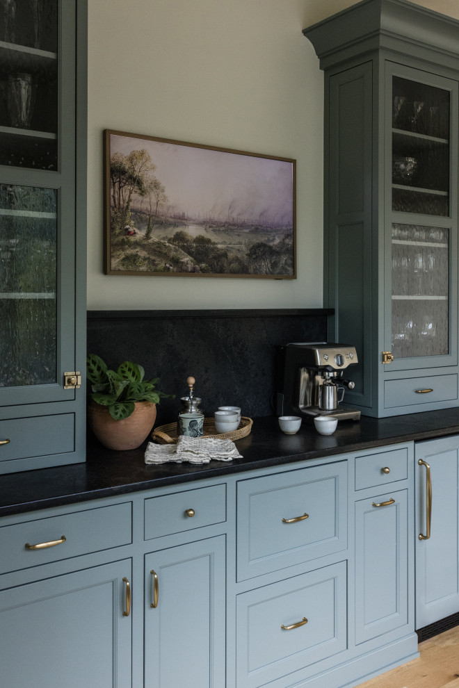 Design ideas for a medium sized traditional single-wall dry bar in Other with no sink, recessed-panel cabinets, light hardwood flooring, engineered stone countertops, black splashback, engineered quartz splashback, white floors and black worktops.