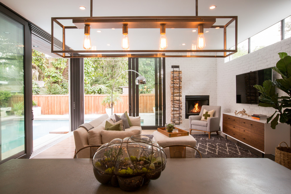 This is an example of a large modern open concept living room in Austin with white walls, medium hardwood floors, a standard fireplace, a brick fireplace surround and a wall-mounted tv.