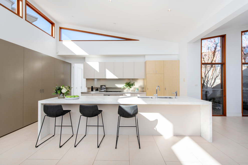 Inspiration for a contemporary galley open plan kitchen in Canberra - Queanbeyan with an undermount sink, flat-panel cabinets, beige cabinets, beige splashback, panelled appliances, with island, beige floor and white benchtop.