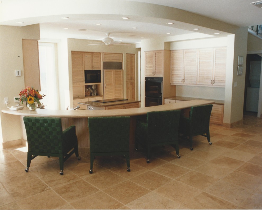 Mid-sized tropical l-shaped eat-in kitchen in San Francisco with an undermount sink, louvered cabinets, light wood cabinets, granite benchtops, beige splashback, glass tile splashback, panelled appliances, travertine floors and with island.