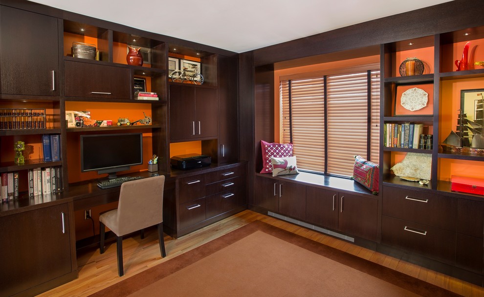 Mid-sized traditional study room in New York with orange walls, light hardwood floors and a built-in desk.