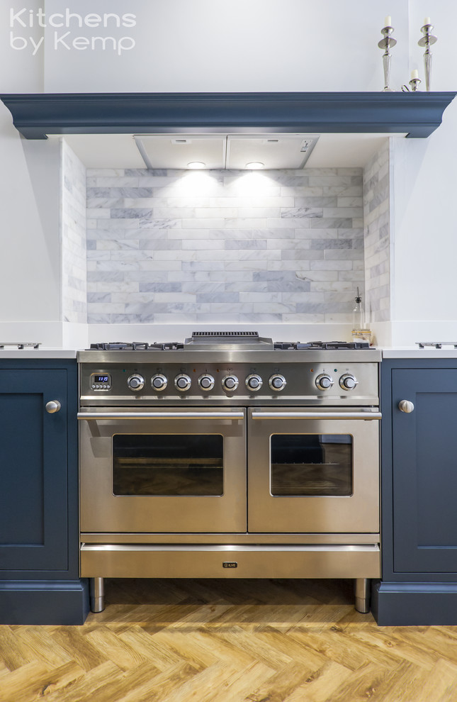 Design ideas for a mid-sized transitional u-shaped open plan kitchen in Cheshire with a single-bowl sink, blue cabinets, quartzite benchtops, blue splashback, marble splashback, stainless steel appliances, vinyl floors, a peninsula, white benchtop and shaker cabinets.