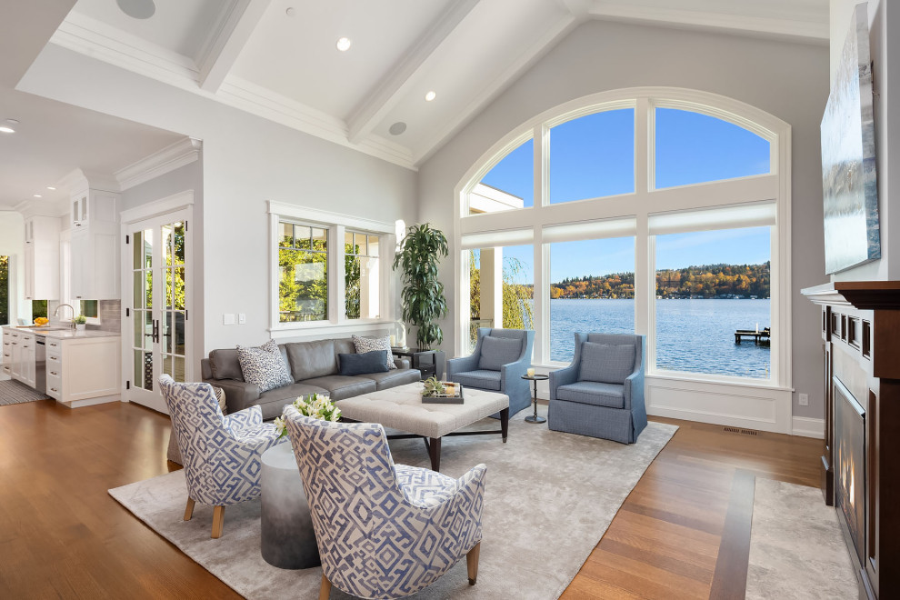 Inspiration for a mid-sized beach style open concept family room in Seattle with grey walls, medium hardwood floors, a stone fireplace surround, a concealed tv and brown floor.