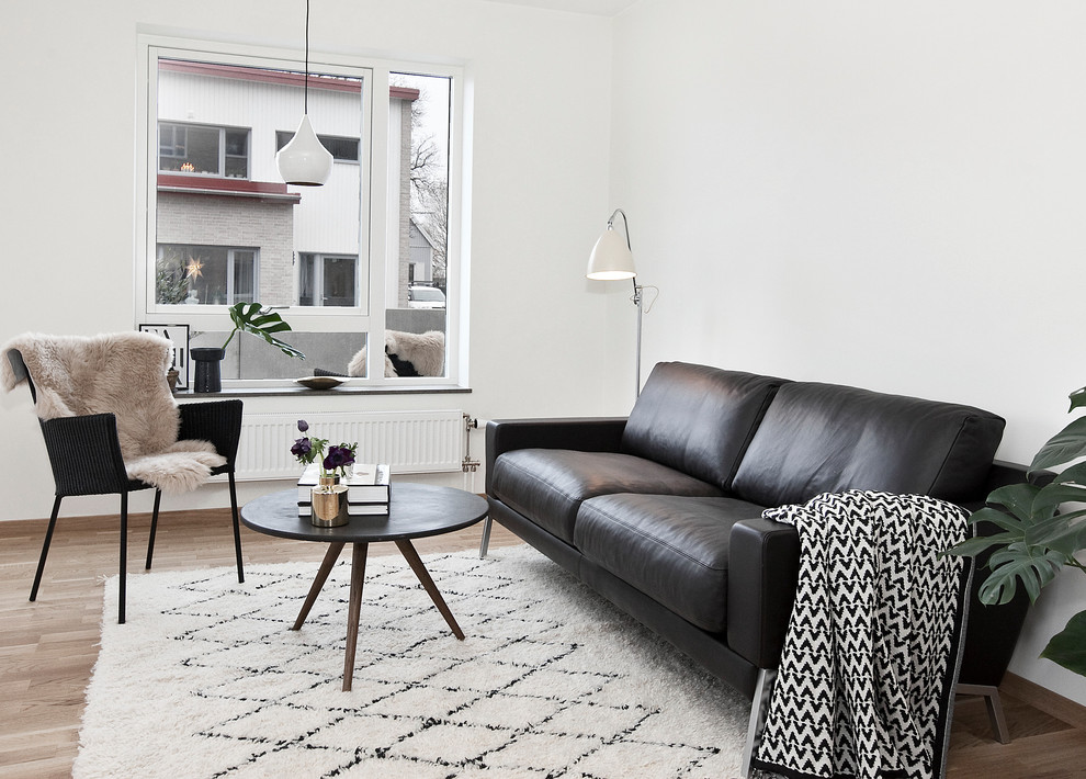 This is an example of a small scandinavian open plan living room in London with white walls, light hardwood flooring and a concealed tv.