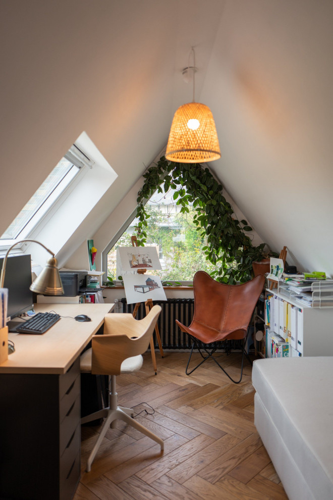 This is an example of a medium sized modern study in Le Havre with white walls, medium hardwood flooring, a freestanding desk and a vaulted ceiling.