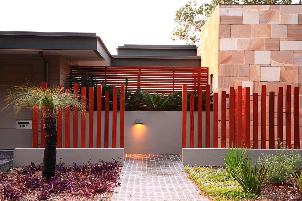 This is an example of a small tropical front yard full sun garden in Sydney with a garden path and brick pavers.