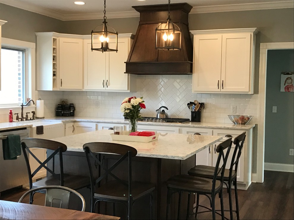 This is an example of a country u-shaped eat-in kitchen in Other with a farmhouse sink, shaker cabinets, white cabinets, quartzite benchtops, white splashback, subway tile splashback, stainless steel appliances, laminate floors and with island.
