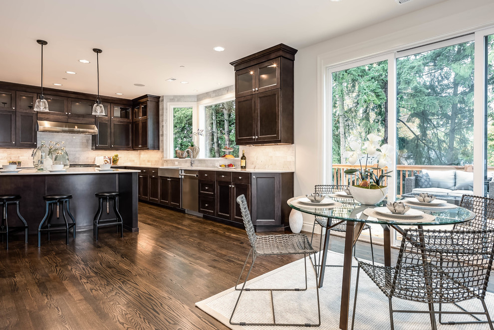 Design ideas for a large transitional u-shaped open plan kitchen in Seattle with a farmhouse sink, recessed-panel cabinets, dark wood cabinets, solid surface benchtops, beige splashback, stone tile splashback, stainless steel appliances, dark hardwood floors and with island.