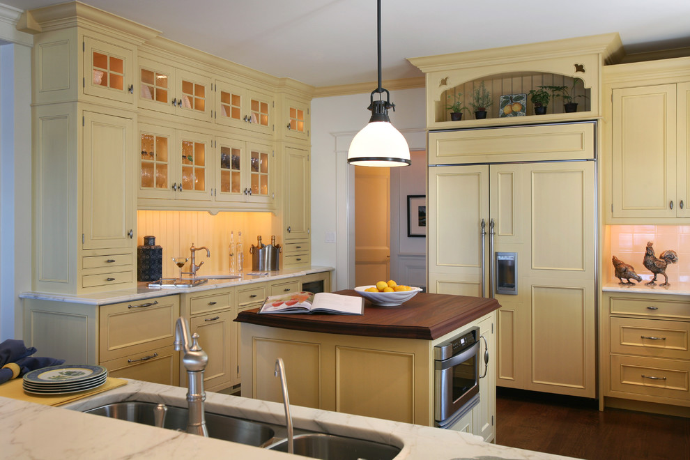 Inspiration for a beach style kitchen in Philadelphia with recessed-panel cabinets, yellow cabinets, wood benchtops and panelled appliances.