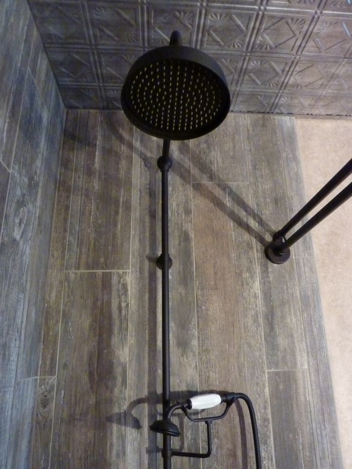 Photo of a mid-sized country 3/4 bathroom in Birmingham with louvered cabinets, dark wood cabinets, an alcove shower, beige tile, black tile, brown tile, gray tile, porcelain tile, a vessel sink and wood benchtops.
