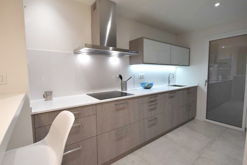 Mid-sized contemporary single-wall open plan kitchen in Barcelona with an undermount sink, flat-panel cabinets, dark wood cabinets, quartz benchtops, white splashback, stainless steel appliances, porcelain floors and grey floor.