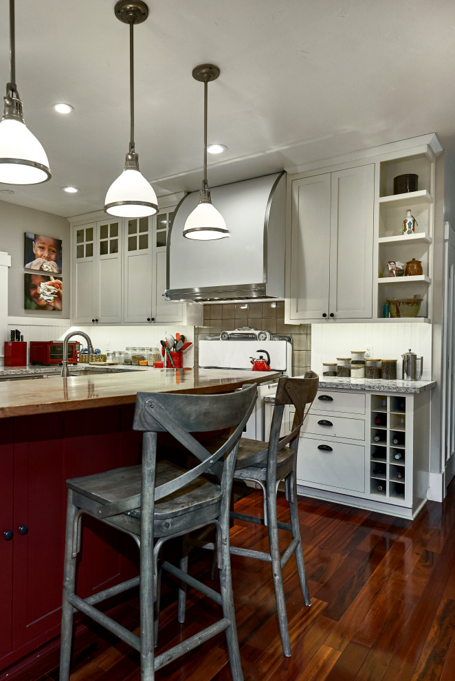 Bild på ett mellanstort amerikanskt grå grått l-kök, med en undermonterad diskho, skåp i shakerstil, vita skåp, granitbänkskiva, vitt stänkskydd, stänkskydd i trä, vita vitvaror, mellanmörkt trägolv, en köksö och rött golv