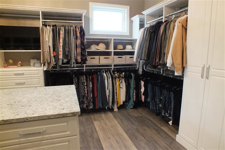 Design ideas for an expansive contemporary gender-neutral walk-in wardrobe in Cleveland with raised-panel cabinets, white cabinets, vinyl floors and brown floor.