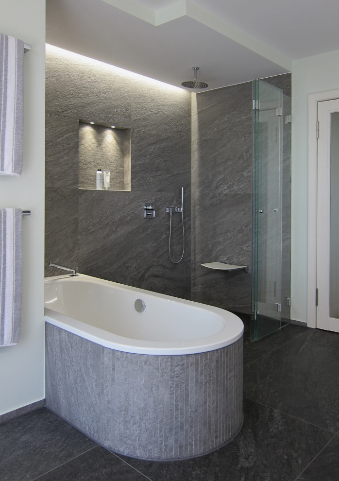 Inspiration for a mid-sized contemporary bathroom in Bonn with a drop-in tub, a curbless shower, a wall-mount toilet, gray tile, ceramic tile, green walls, ceramic floors, solid surface benchtops, grey floor, a hinged shower door and white benchtops.