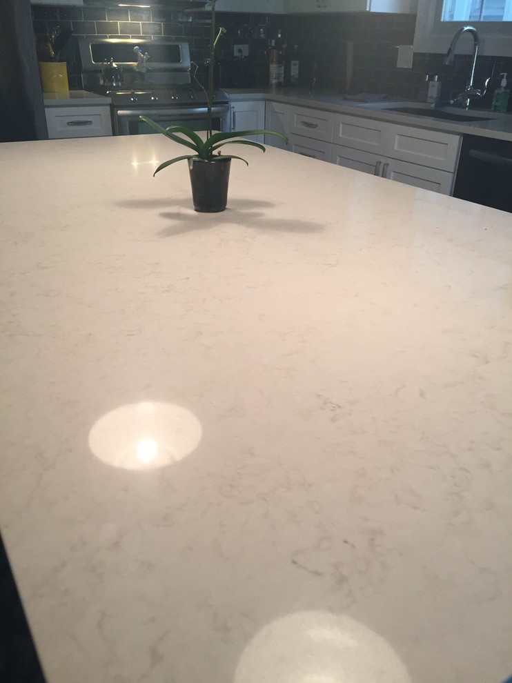 Transitional l-shaped kitchen photo in Chicago with an undermount sink, shaker cabinets, white cabinets, quartz countertops, gray backsplash, subway tile backsplash, stainless steel appliances and an island