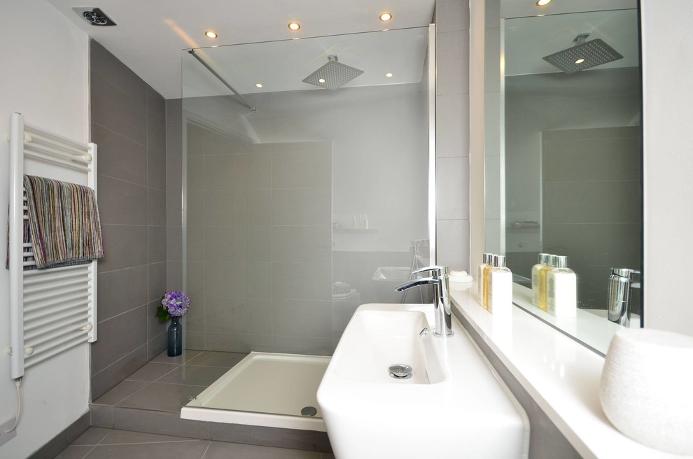 Photo of a mid-sized modern master bathroom in London with an open shower, a wall-mount toilet, white tile, porcelain tile, white walls, porcelain floors, a wall-mount sink and soapstone benchtops.