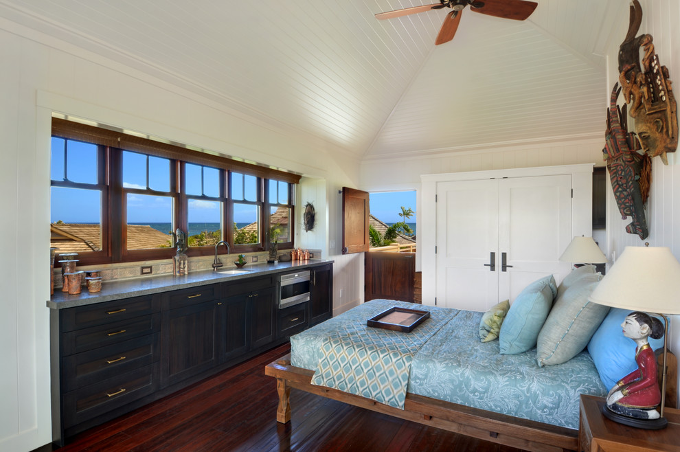 Photo of a tropical bedroom in Hawaii with beige walls and dark hardwood floors.