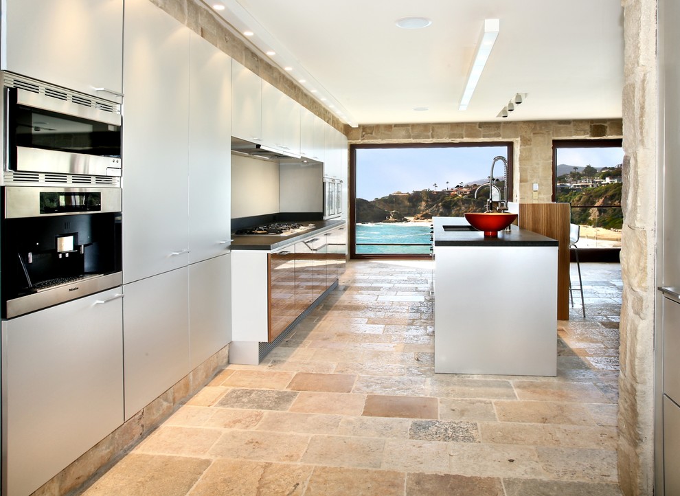 Inspiration for a mediterranean galley kitchen in Orange County with limestone floors, an undermount sink, flat-panel cabinets, white cabinets, stainless steel appliances and with island.