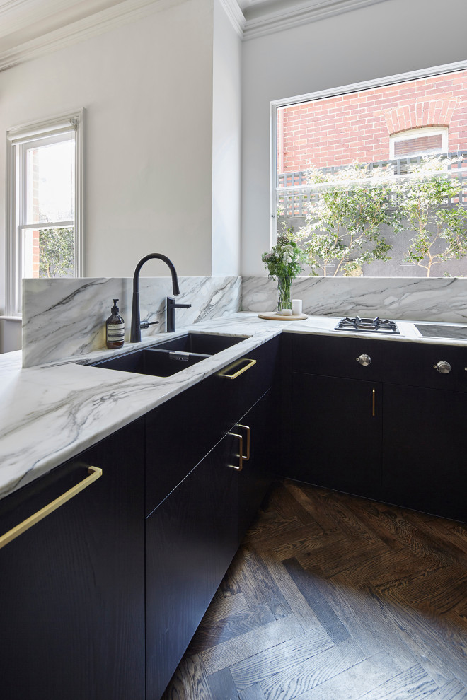 This is an example of a mid-sized traditional u-shaped eat-in kitchen in Melbourne with a double-bowl sink, black cabinets, marble benchtops, multi-coloured splashback, marble splashback, stainless steel appliances, medium hardwood floors, with island, brown floor and multi-coloured benchtop.