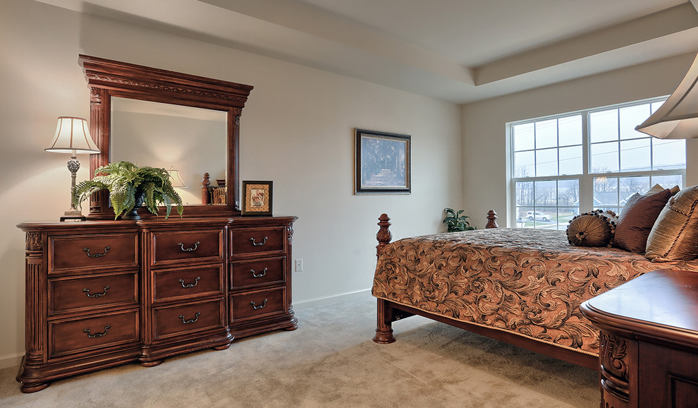 Large traditional master bedroom in Other with beige walls and carpet.