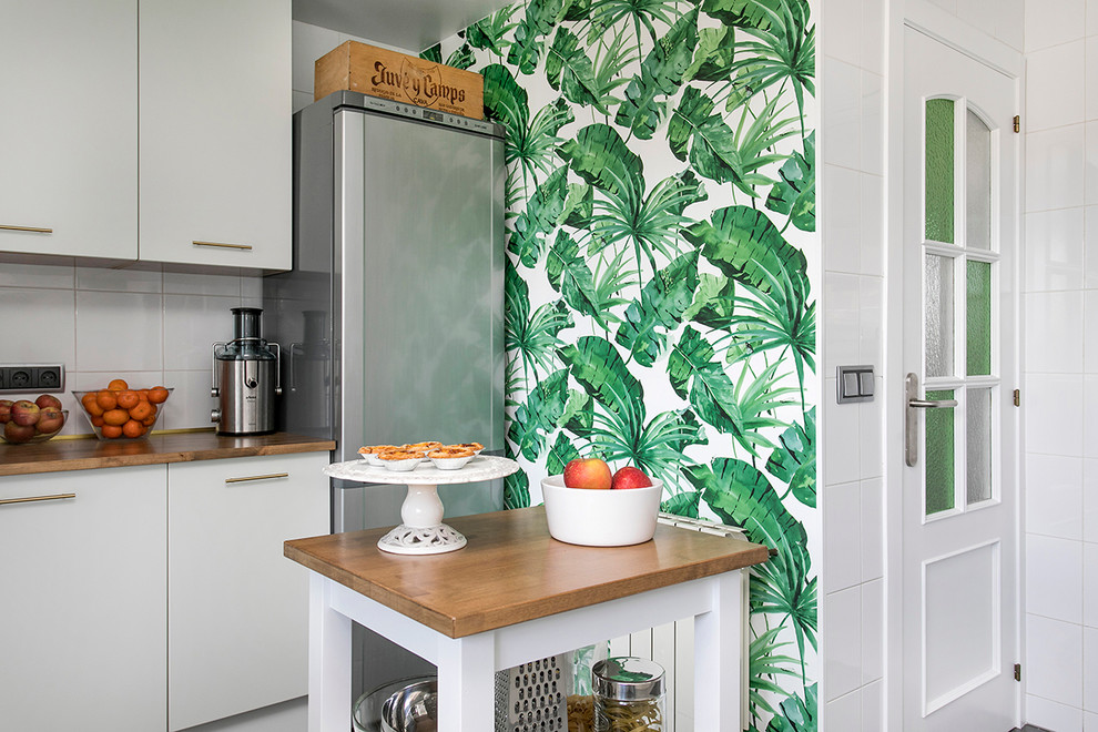 Photo of a mid-sized tropical kitchen in Barcelona with flat-panel cabinets, white cabinets, wood benchtops, with island and brown benchtop.