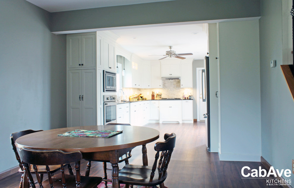 Example of a mid-sized transitional l-shaped vinyl floor and brown floor eat-in kitchen design with an undermount sink, recessed-panel cabinets, white cabinets, quartz countertops, beige backsplash, ceramic backsplash, stainless steel appliances and no island