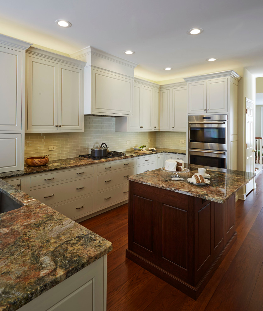 Inspiration for a mid-sized transitional u-shaped medium tone wood floor enclosed kitchen remodel in Chicago with a single-bowl sink, raised-panel cabinets, white cabinets, granite countertops, white backsplash, glass tile backsplash, stainless steel appliances and an island
