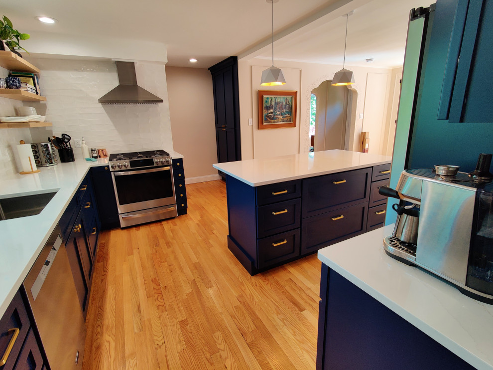 Large transitional u-shaped medium tone wood floor and red floor eat-in kitchen photo with an undermount sink, shaker cabinets, blue cabinets, quartzite countertops, white backsplash, ceramic backsplash, stainless steel appliances, an island and white countertops