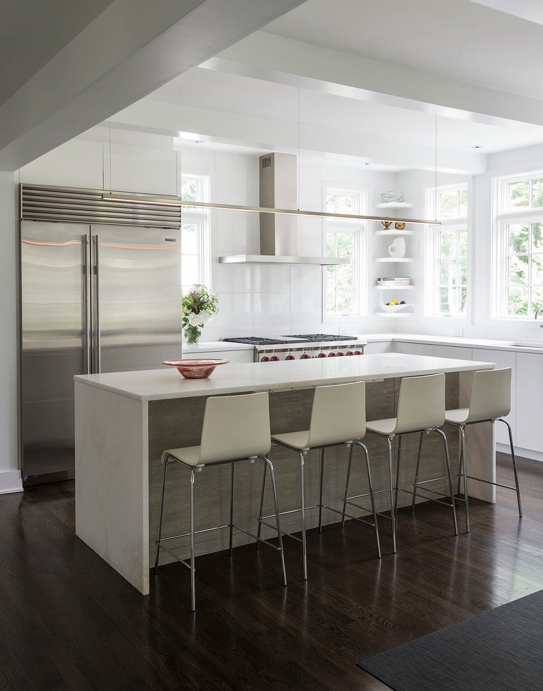 Inspiration for a large contemporary l-shaped eat-in kitchen in New York with an undermount sink, white cabinets, white splashback, dark hardwood floors, with island, flat-panel cabinets, solid surface benchtops, stainless steel appliances and glass sheet splashback.