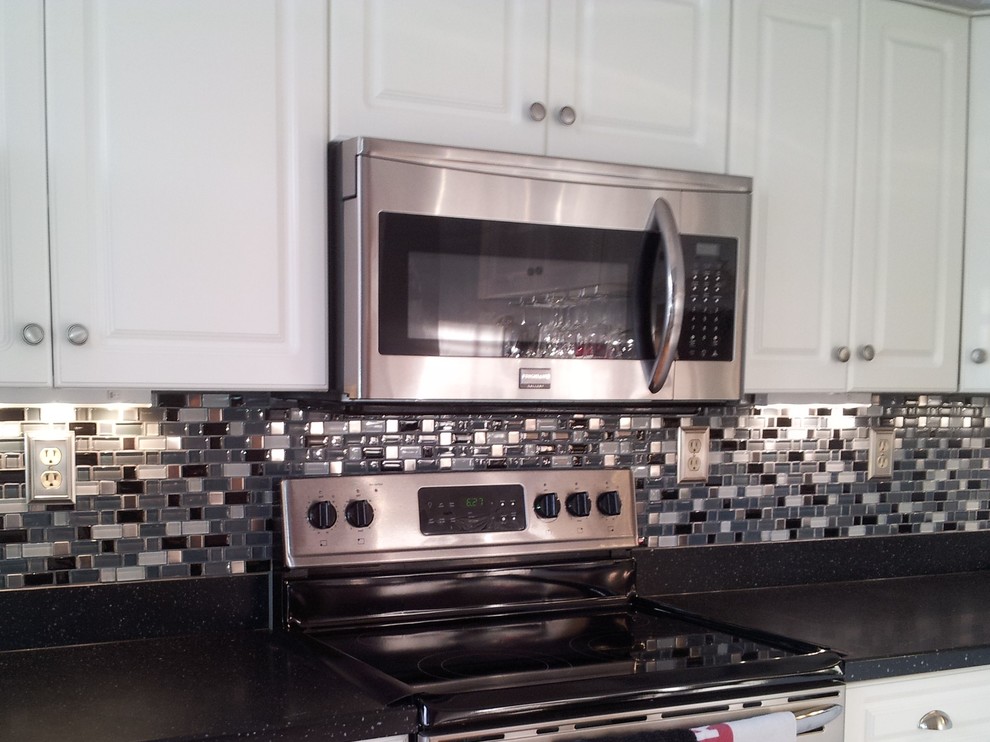 Inspiration for a contemporary kitchen remodel with raised-panel cabinets, white cabinets, quartz countertops, multicolored backsplash, mosaic tile backsplash and stainless steel appliances