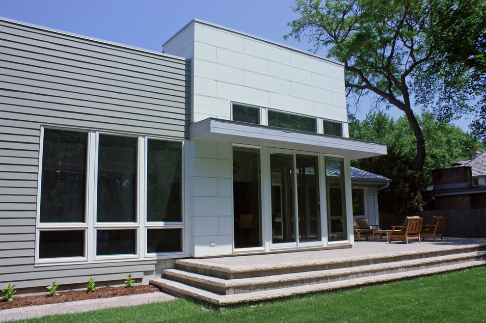 This is an example of a mid-sized midcentury split-level white exterior in Chicago with concrete fiberboard siding.