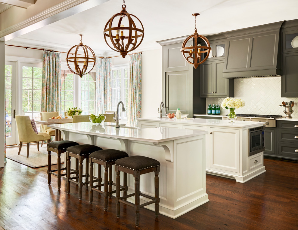 Eat-in kitchen - traditional medium tone wood floor eat-in kitchen idea in Charlotte with recessed-panel cabinets, white backsplash, ceramic backsplash, stainless steel appliances and two islands