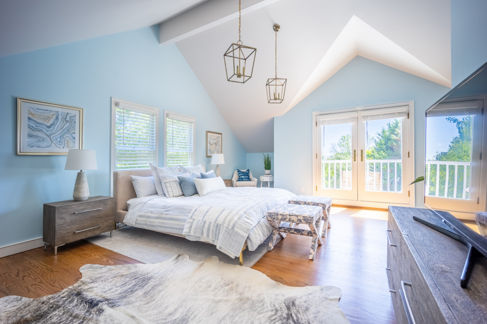 This is an example of a large coastal master bedroom in New York with blue walls, medium hardwood flooring and a vaulted ceiling.