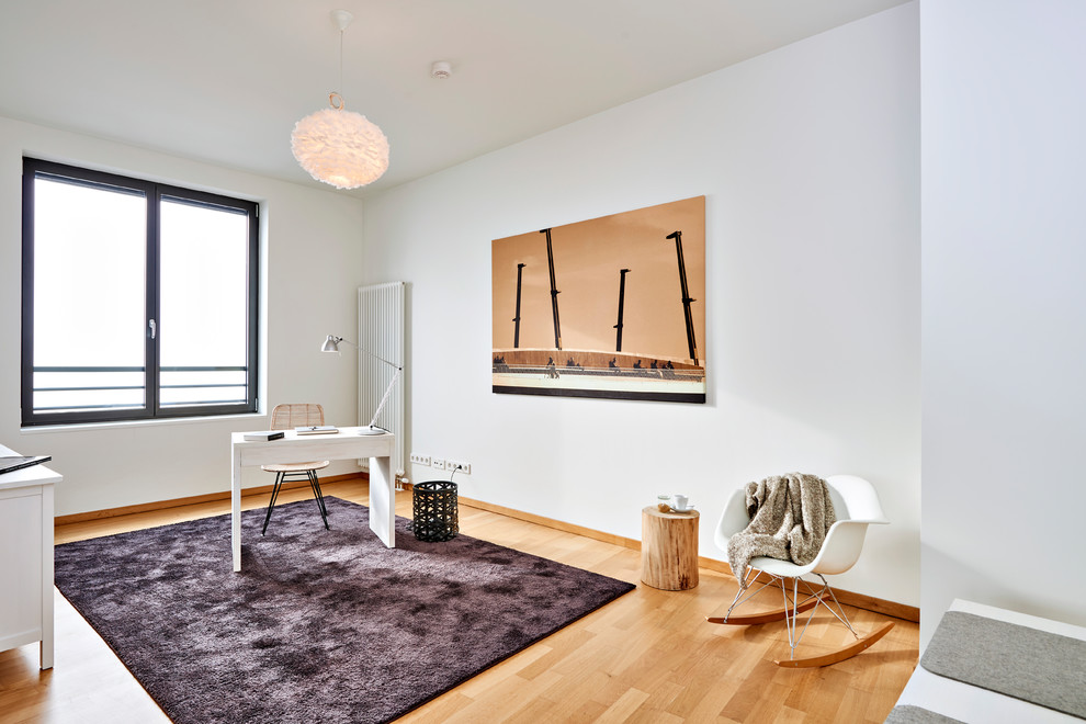 Kleines Nordisches Arbeitszimmer mit Arbeitsplatz, weißer Wandfarbe, braunem Holzboden, freistehendem Schreibtisch und braunem Boden in Hamburg